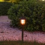 Lampe solaire flamme installée dans un jardin, émettant une lumière chaude et scintillante, parfaites pour éclairer allées et patios avec élégance.