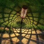 Lampe solaire LED jardin projetant une ombre décorative en motif géométrique sur l’herbe et sol