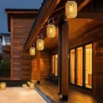 Lanternes solaires LED en rotin suspendues sous un auvent en bois, ambiance chaleureuse extérieure