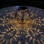 Lanterne solaire projetant des motifs soleil lumineux sur une table en soirée.