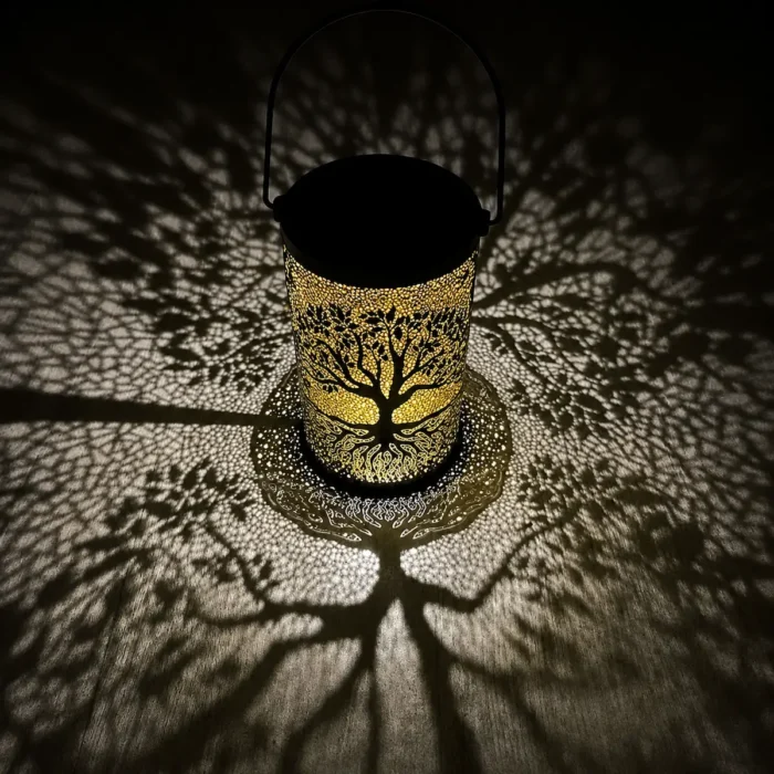 "Lanterne solaire décorative motif arbre projetant de grandes ombres lumineuses sur le sol dans une ambiance nocturne poétique."