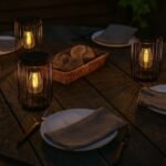 Lampes solaires LED blanc chaud en métal, posées sur une table de jardin pour créer une ambiance conviviale en soirée.