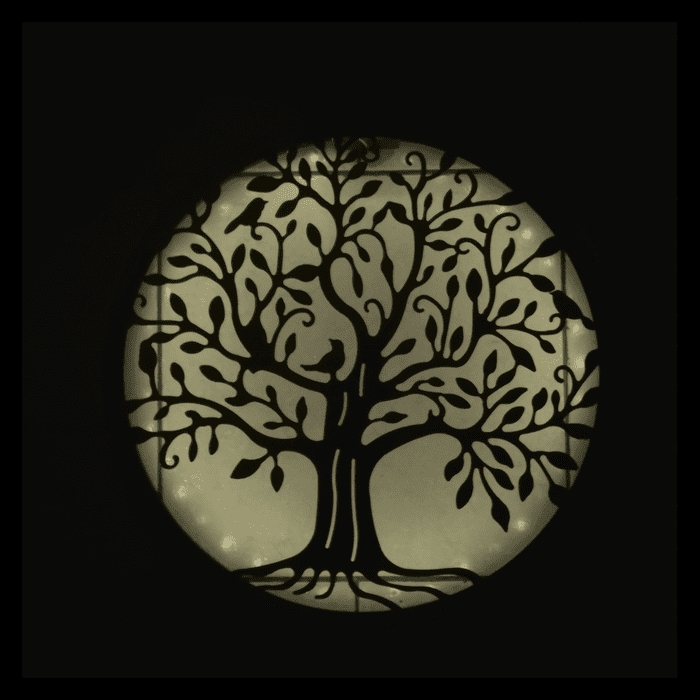 Lampe murale solaire arbre de vie illuminée en blanc chaud, ambiance zen et décorative de nuit.