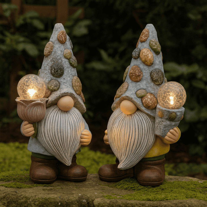 Deux nains de jardin Solaire décoratifs côte à côte sur une pierre recouverte de mousse, tenant des boules lumineuses allumées, dans un décor de jardin naturel.