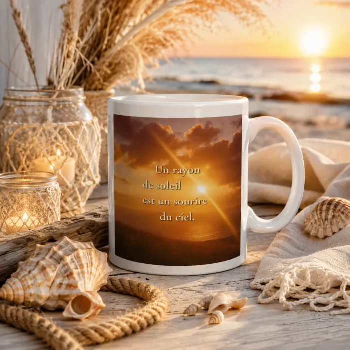 "Mug blanc citation « Un rayon de soleil est un sourire du ciel » en mise en scène bord de mer avec coquillages, corde et lumière dorée"