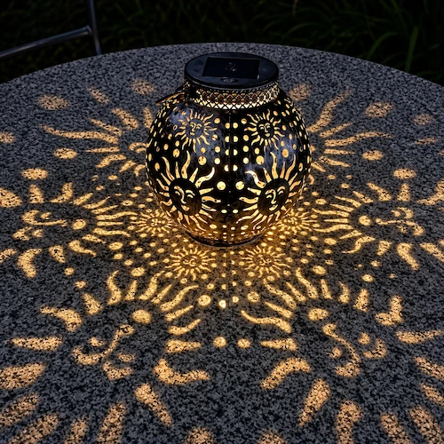 Lanterne solaire posée sur une table la nuit avec motif soleil qui reflète.